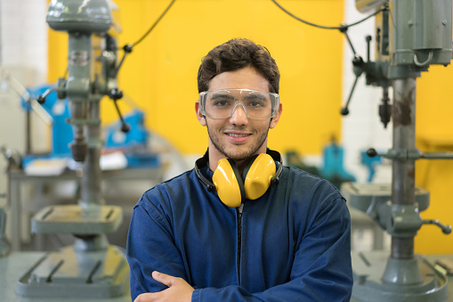 Portrait of an engineering student at the university wearing protective wear and smiling - education concepts