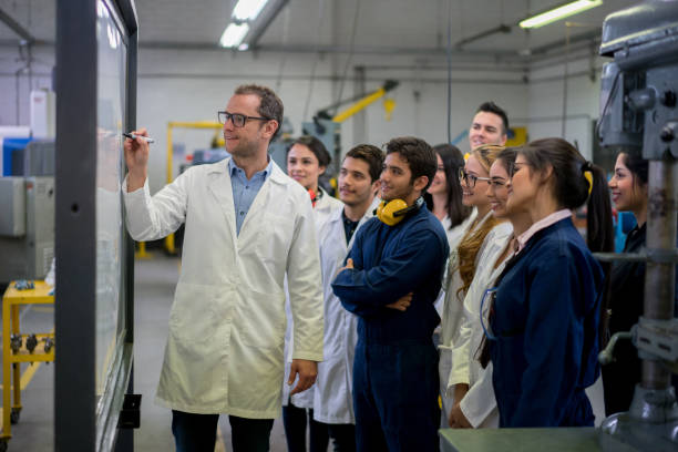 Engineering students with their teacher writing on the board Happy group of engineering students with their teacher writing on the board at the university - education concepts industrial designer stock pictures, royalty-free photos & images