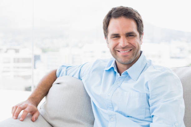 istock Smiling handsome man sitting on the couch looking at camera 691713176