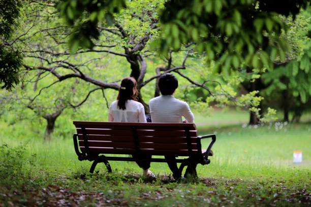 istock Young couple on bench enjoying spring at park 691723562