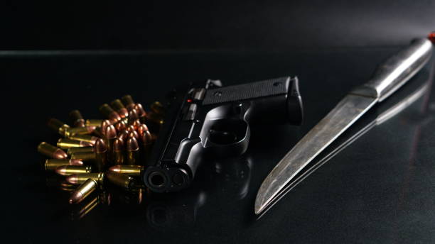 istock Bullets, knife and a gun on black mirror 691726488