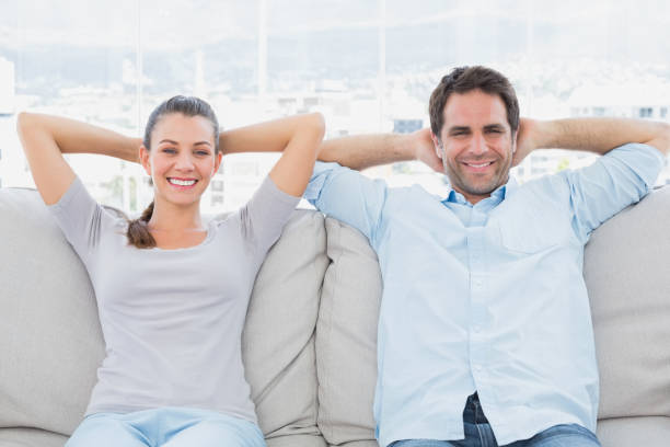 istock Happy couple relaxing on the couch smiling at camera 691730414