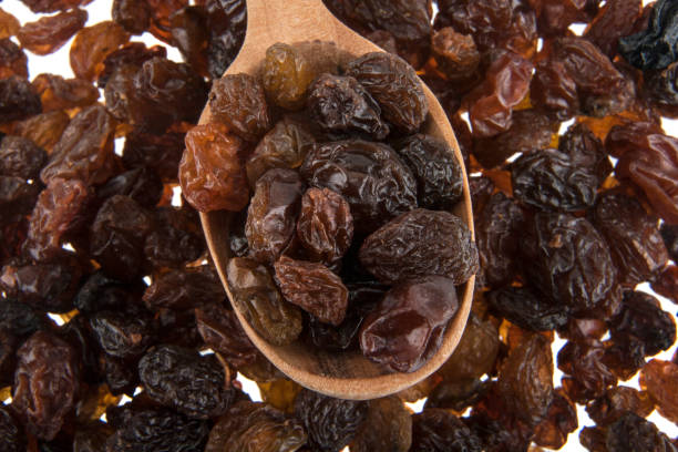 istock Raisins and wooden spoon isolated on white background 691733894