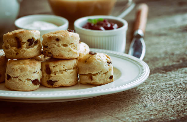 scones aux raisins maison accompagner de confiture de fraises maison, crème caillée et thé. ensemble de crème scones sur la plaque blanche. scones est une pâtisserie anglaise thé thé, crème. scones de comté de devon et cornish cream scones. - cornish cream tea photos et images de collection