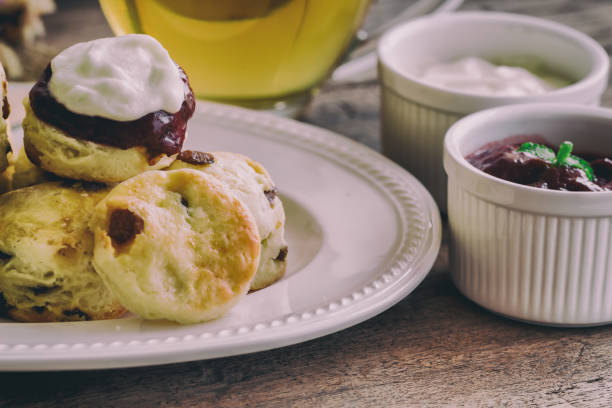 scones aux raisins maison accompagner de confiture de fraises maison, crème caillée et thé. ensemble de crème scones sur la plaque blanche. scones est une pâtisserie anglaise thé thé, crème. scones de comté de devon et cornish cream scones. - cornish cream tea photos et images de collection