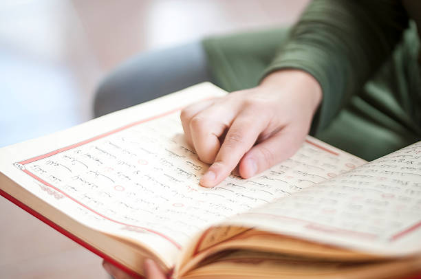 joven leyendo el corán - single word islam religion text fotografías e imágenes de stock