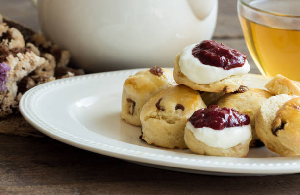 bolinhos de passas caseiras servem com geleia de morangos caseira, creme de leite e chá. conjunto de scones de creme na chapa branca. scones é bolo inglês para chá da tarde chá, creme. scones do condado de devon e da cornualha scones de creme. - cornish cream tea - fotografias e filmes do acervo