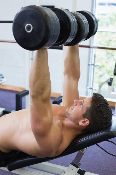 istock Shirtless bodybuilder lifting heavy dumbbells lying on bench 691737964