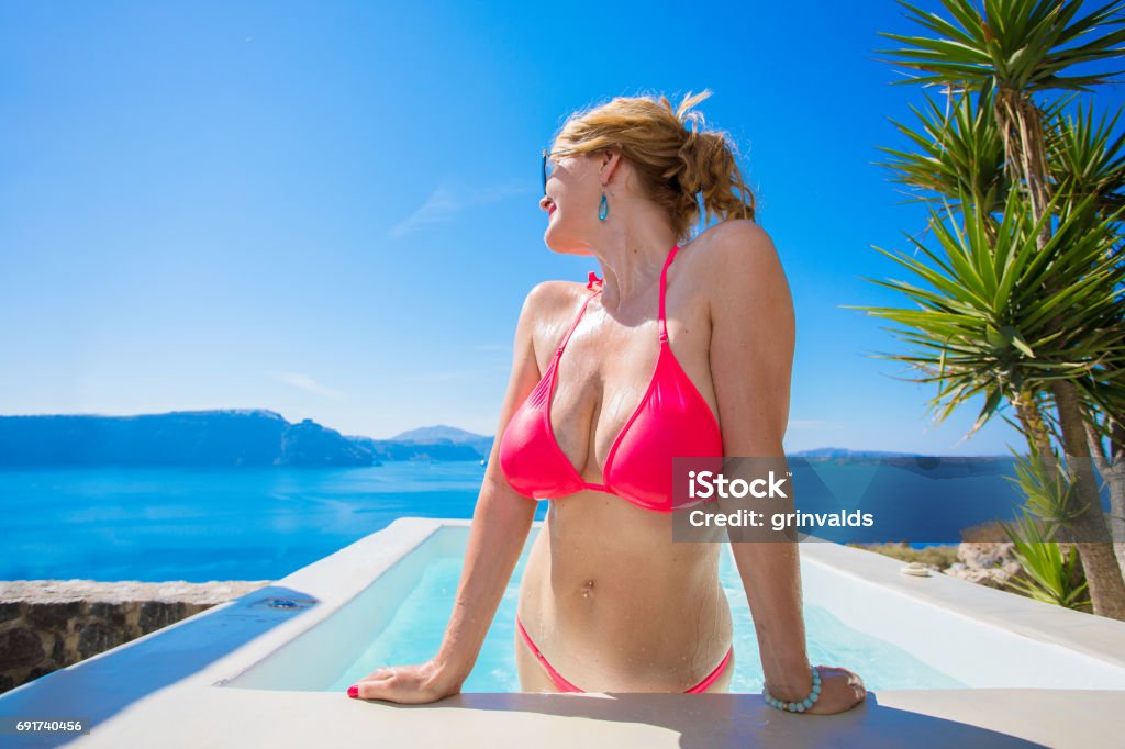 Sexy woman in pink bikini Sexy woman in pink bikini in swimming pool looking at sea Breast Stock Photo