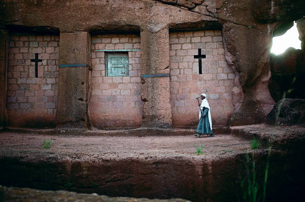 Pilgram Prayer Female walking in front of old rock building and church with blue window and dress at dawn Lalibela Ethiopia Horn of Africa ethiopia photos stock pictures, royalty-free photos & images