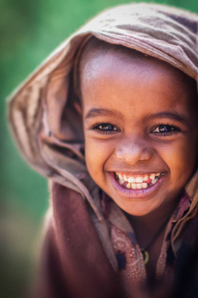 Pretty and Strong Portrait of Beautiful African girl in brown traditional clothing and head scarf smiling Lalibela Ethiopia Horn of Africa