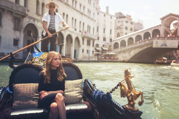 mujer joven en el tour de góndola en venecia, con el puente de rialto en el fondo - venice italy rialto bridge italy gondola fotografías e imágenes de stock