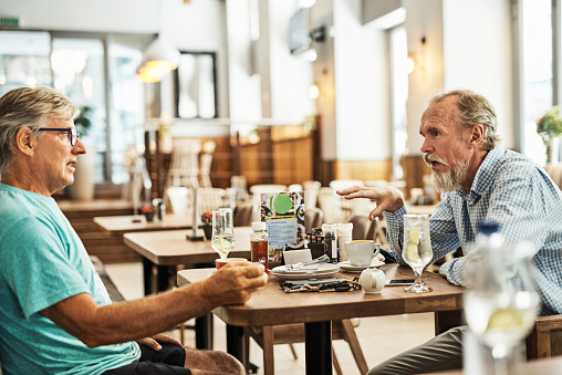 Shot of two senior friends chatting at a table at their favorite cafe