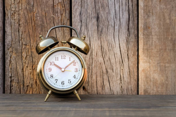 istock alarm clock on the wood table with soft light and old wood background 691754724