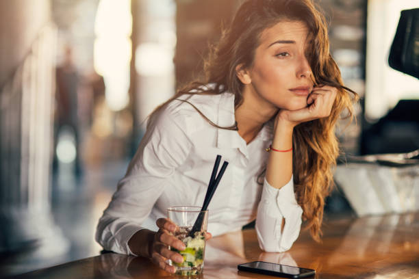 Woman drinking cocktail in a bar Bored woman drinking cocktail at a bar. drunk stock pictures, royalty-free photos & images