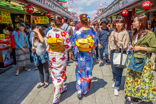 Tokyo, Japan - April 19, 2017: women's back in japanese kimonos walking in spring sakura on Nakamise-dori, a street with food and souvenirs shops. Senso-ji Buddhist Temple in Asakusa area, Tokyo.