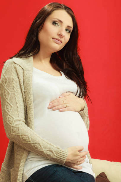 istock Sitting pregnant woman showing belly 691768268