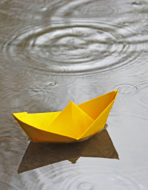 istock yellow paper boat in an puddle 691773076