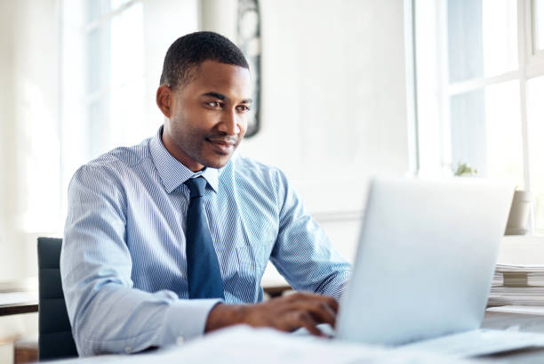 He’s the best when it comes to business Cropped shot of a handsome young businessman working on a laptop in an office laptop businessman business men stock pictures, royalty-free photos & images