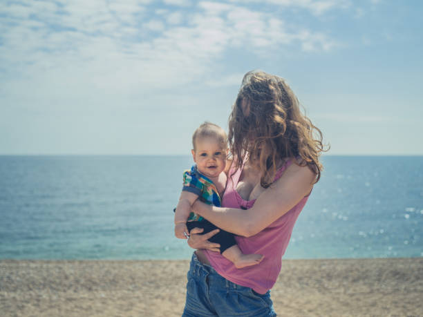 istock Mother standing on beach with baby 691785146