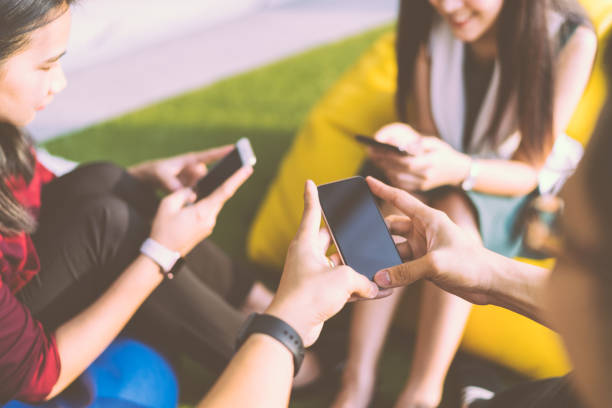 istock Group of three young people using smartphones together, modern lifestyle or communication technology gadget concept, depth of field effect 691786412