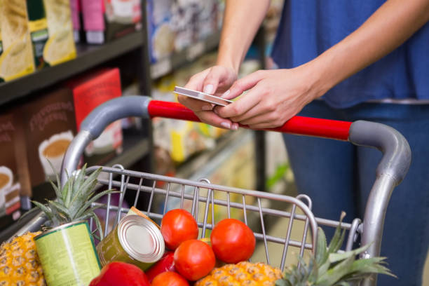 istock Pretty woman pushing trolley in aisle and texting 691786928