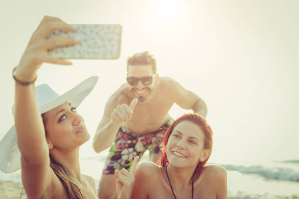 Friends at sea: photobombing in a selfie Friends at sea: relaxing on the beach at sunset photo bomb stock pictures, royalty-free photos & images