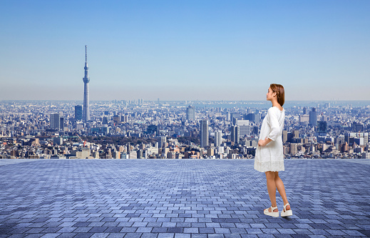 young girl standing on an observation platform and modern cityscape panorama