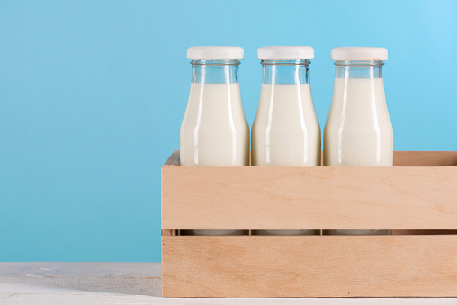 Close-up view of fresh organic milk in glass bottles in box on blue