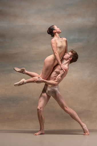 Couple of ballet dancers posing over gray background.