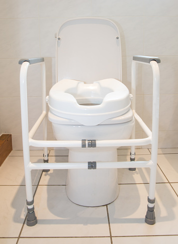 Toilet with raised seat to assist infirm or recovering patients - with handrail to push from