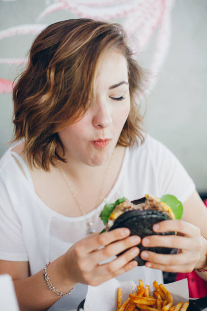 istock Woman eating black burger 691812802