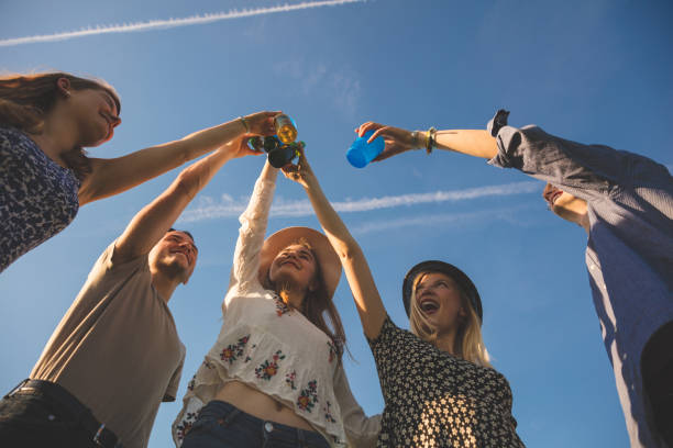 Low angle view of friends toasting drinks against blue sky