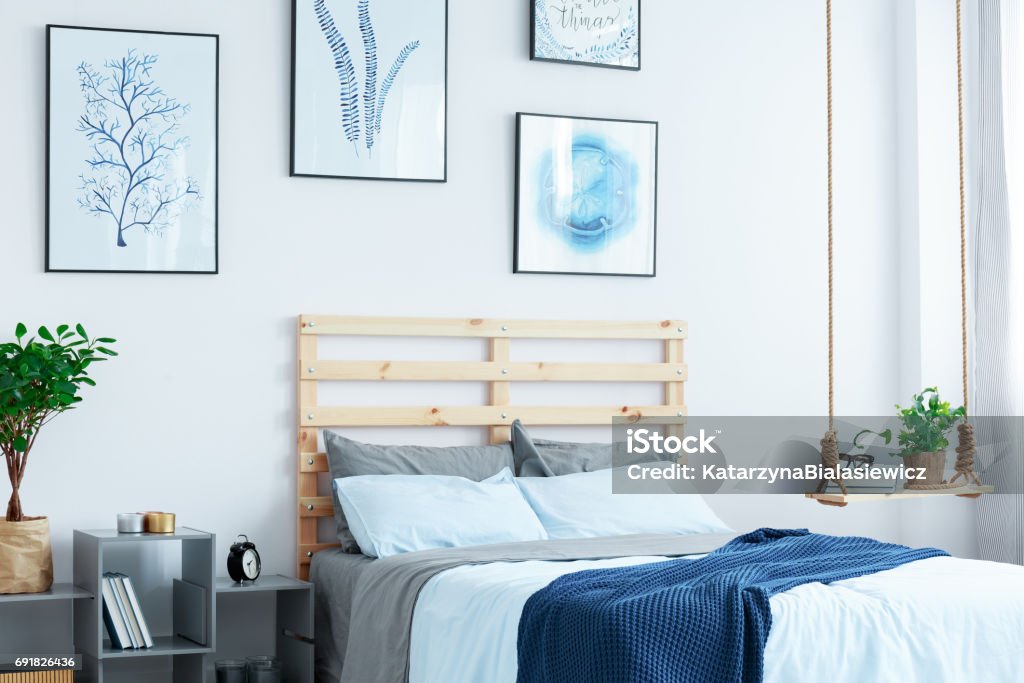 White bedroom with wood bed White bedroom with wood bed, swing shelf, wall posters, plants Apartment Stock Photo