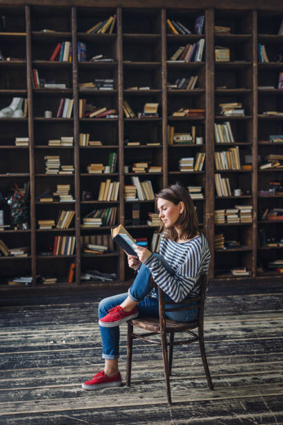 joven leyendo en la biblioteca - smart casual women full length casual fotografías e imágenes de stock