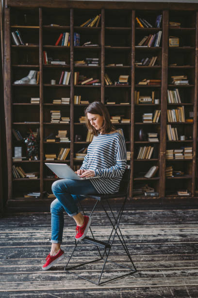 Young woman studying in the library Young woman using laptop in the library author stock pictures, royalty-free photos & images