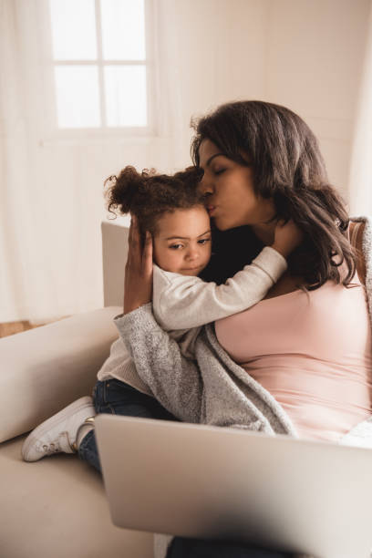 istock Mother using laptop while hugging and kissing cute little daughter 691846678