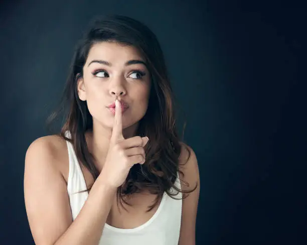 Studio shot of a beautiful young woman posing with her finger on her lips