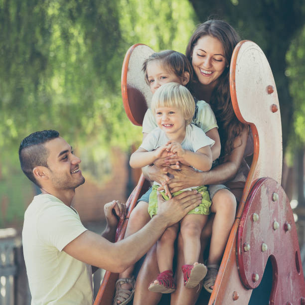 istock Smiling parents helping kids on slide 691857364