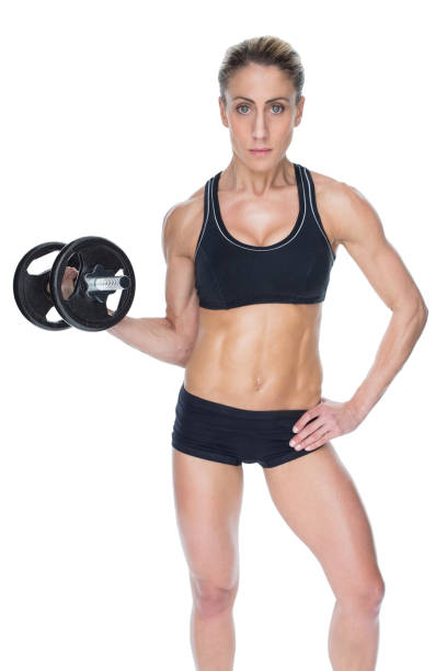 istock Female bodybuilder holding large black dumbbell with arm up looking at camera 691872642