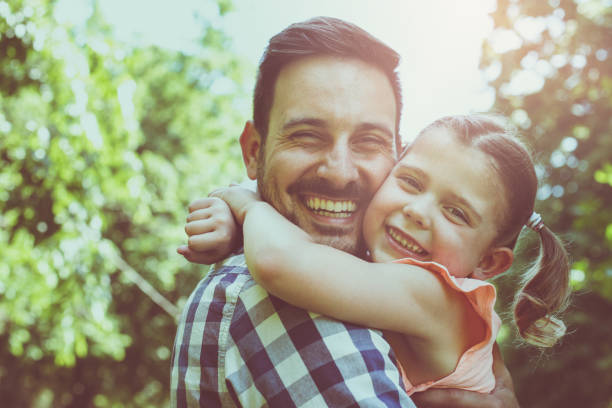 istock Father holding his daughter in his arms and looking at camera. 691875370