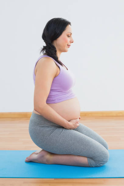 istock Happy pregnant brunette kneeling on exercise mat 691875614