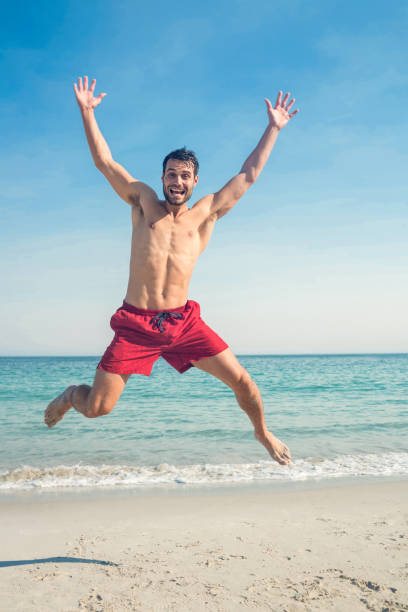 Happy man jumping on the beach on a sunny day