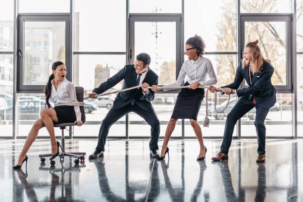 istock businesswoman bound with rope on chair and multicultural business team pulling her 691878236