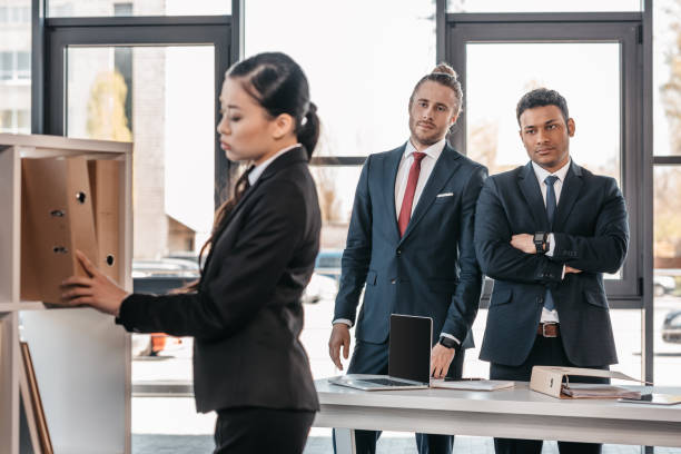 istock businesswoman holding folder while colleagues standing and looking behind 691882360