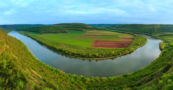 Top picturesque evening view of the Dnister river bend canyon, with spring fields on coast. Ternopil region, Ukraine, Europe. Two shots stitch panorama.