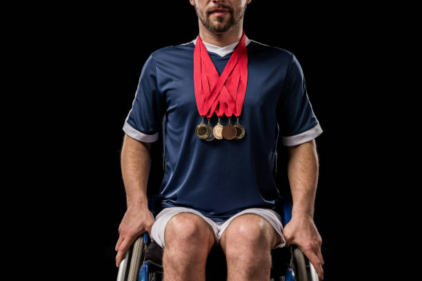 обрезанный вид паралимпийских в инвалидной коляске с золотыми медалями на шее изолированы на черном - olympic athlete muscular build winning стоковые фото и изображения