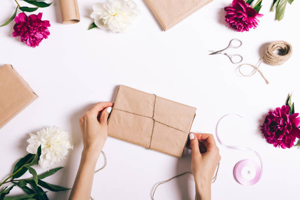 istock Female hands wrapping presents on a white table 691886564