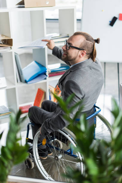 istock young physically handicapped businessman in glasses doing paperwork at office 691888764