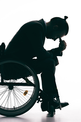 silhouette of depressed man sitting in wheelchair isolated on white